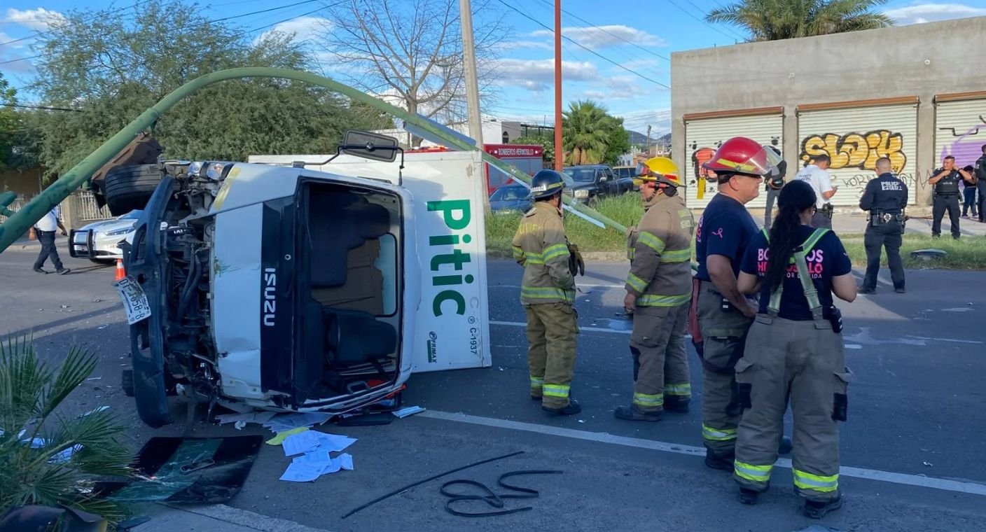 Se vuelca unidad de carga tras chocar con auto y derriba semáforo en Hermosillo; Bomberos rescatan al conductor